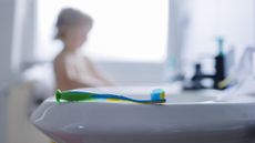 A toothbrush rests on the edge of a sink.