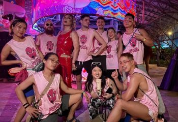 Group of gay men at Medusa Realness event, Thailand. Pink Medusa shirts, red latex outfit. Gay travel, LGBTQ+ pride, music festival.