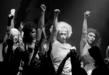 Black and white image of drag queens with fists raised in solidarity. Medusa Realness and LGBTQ+ pride are demonstrated.
