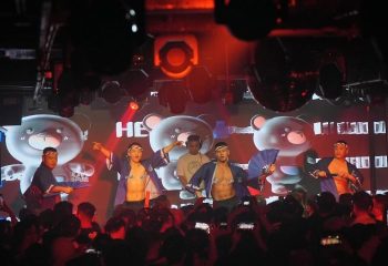 Gay travel destination: Go-go dancers entertain a crowd at a gay club. Nightlife scene with shirtless men. Party atmosphere.