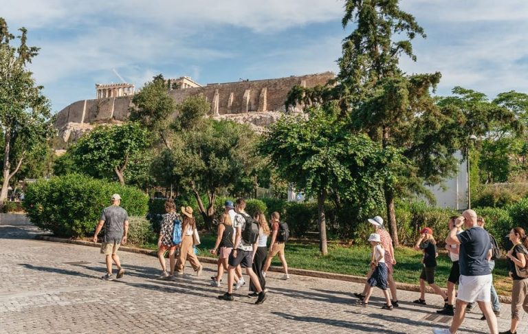 Acropolis & Parthenon exploration with expert guide in Athens. Group of tourists walking towards the Acropolis on a sunny day. Gay travel.