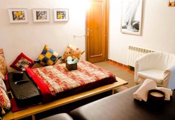 Adoneys Gay Massage in Madrid: Cozy massage room with futon, pillows, and massage table. A relaxing space for gay men's wellness.