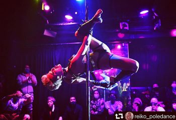 Pole dancer at AiSOTOPE Lounge, a gay dance club in Tokyo. Part of a gay Tokyo travel guide. Dark room, stage, and audience visible.