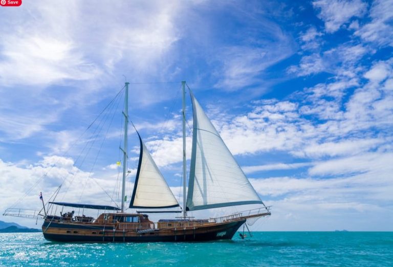 Ang Thong Discovery Cruise. Gay travel to Koh Samui: Wooden sailing yacht on turquoise sea with blue sky. Full day escape for gay men.