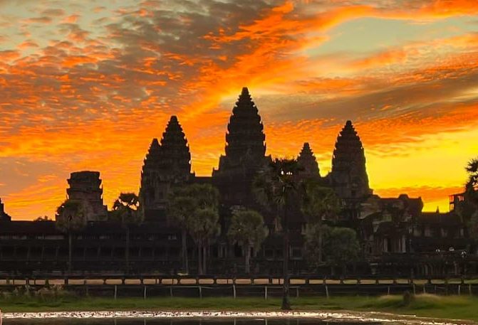 Angkor Wat sunrise. Iconic temples in Siem Reap, Cambodia, offer gay travel adventure. Sunset view with orange & yellow sky.