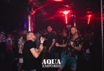 Aqua Emporio gay cruise club in Torremolinos. Gay men dancing under red lights & disco ball. Nightlife scene perfect for gay travel.