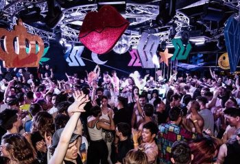 Arq Sydney: Gay men dance at a crowded nightclub with colorful decorations. Nightlife scene, travel advice for LGBTQ+ visitors.