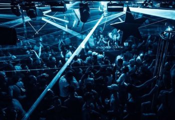 Arq Sydney gay club: A packed dance floor with blue laser lights and a DJ in the background. Nightlife for gay men's travel advice.