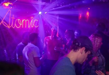 Atomic Frankfurt: Gay nightlife at Atomic von Herzen. Nightclub scene with purple lights, people, and the Atomic sign.