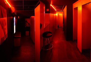 Attraxx Athens: Interior of a gay sauna with red lighting, cubicles, and a stool. Gay travel advice for Athens, Greece.