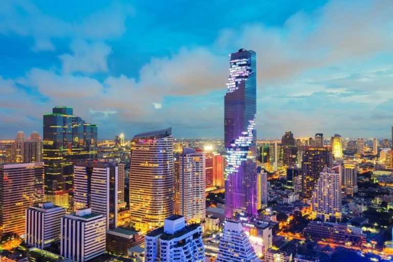 Bangkok SkyDeck Viewing Ticket: Cityscape view at dusk, featuring modern skyscrapers illuminated against a twilight sky. Bangkok travel for gay men.