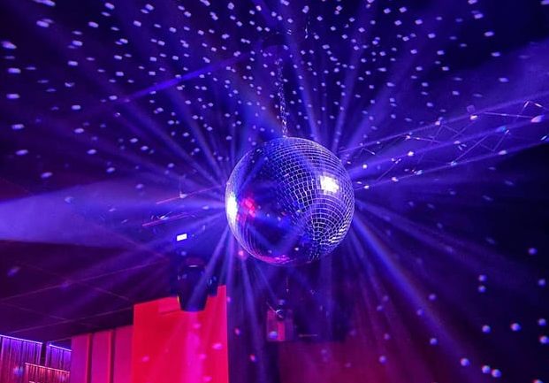 Disco ball reflecting purple lights. Gaixample hot spots, queer vibes. Barcelona gay nightlife tour. Party atmosphere.