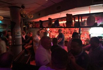 Inside Bear's Bar, Benidorm. Gay men gather for drinks, creating a lively party atmosphere. The bar is well-stocked and decorated.