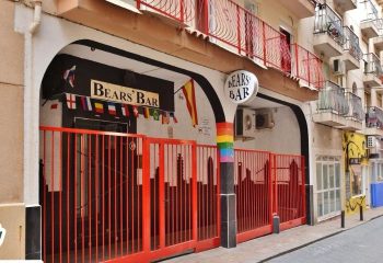 Bear's Bar in Benidorm, a gay-friendly destination. Red gates, rainbow pillar, and international flags adorn the entrance for drinks & party.