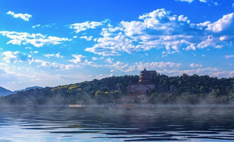 Beijing Summer Palace Temple of Heaven tours. Gay-friendly travel photo of a pagoda on a hill by a misty lake under a blue sky.