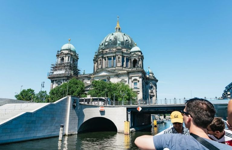 Berlin River Cruise: Men enjoy a luxe boat tour with guaranteed seats, viewing the iconic Berliner Dom on a sunny day.