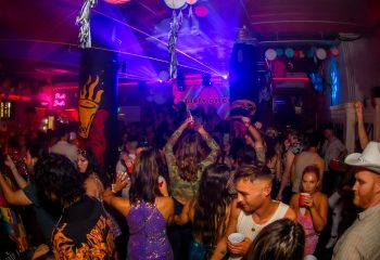 Crowd partying at Burdekin Hotel Sydney's gay bar. People are dancing under colorful lights at a Dirty Disco night. Gay travel advice.