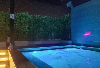 Krubb Bangkok pool. Outdoor jacuzzi with blue lighting, waterfall feature, and lush greenery. Gay travel advice in Bangkok, Thailand.