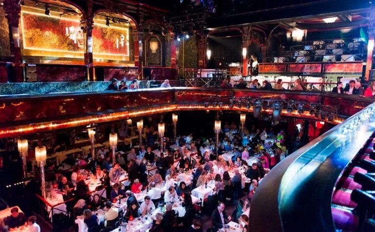 Paris Nights at Paradis Latin cabaret show. Attendees at tables in the theater. Champagne and cabaret, a gay men travel destination.