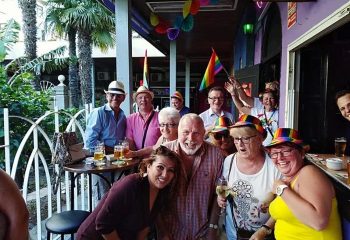 Chessa Bar, a gay bar in Torremolinos. Group of happy people with rainbow hats and flags, enjoying drinks at this popular gay venue.