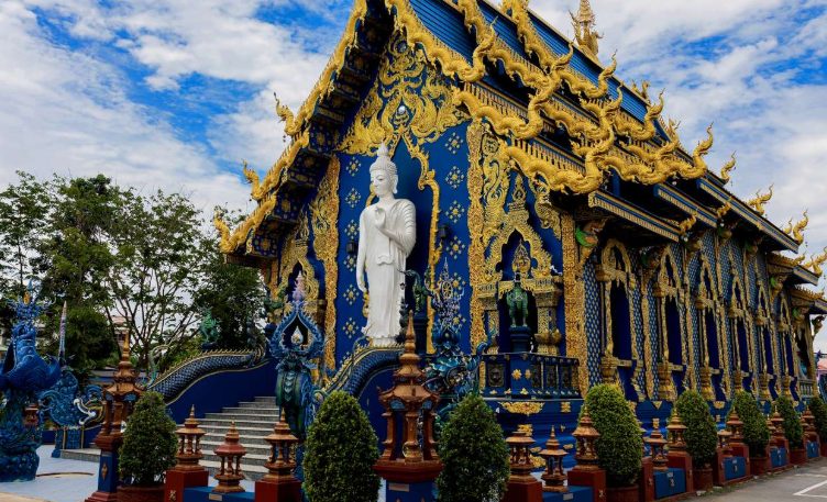 Chiang Rai's Blue Temple, a Golden Triangle highlight on a gay-friendly tour. This ornate temple features intricate gold detailing & a Buddha statue.
