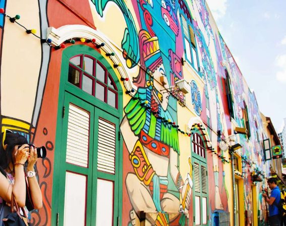 Colorful mural in Singapore's Chinatown and Little India. Guided walking tour, vibrant street art, tourist taking photos. Gay travel advice.