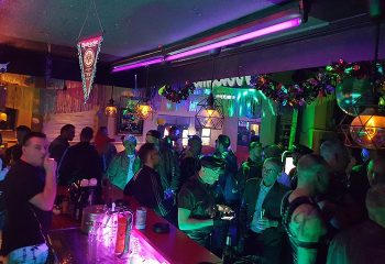 Inside Comeback Bar, Frankfurt. A busy gay bar scene with men socializing under colorful lights. Frankfurt's gay nightlife.