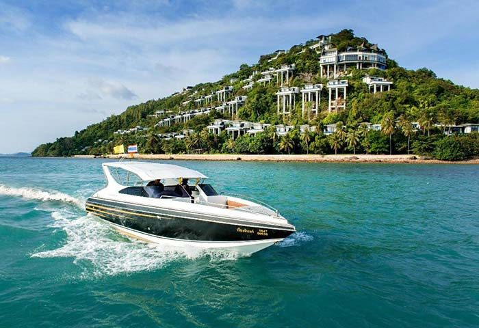 Conrad Koh Samui gay-friendly resort: speedboat on turquoise water. Villas dot a lush hillside. Perfect for gay travel & luxury vacations.