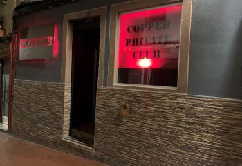 Copper Private Club in Benidorm, a gay cruising location. Red neon sign illuminates the entrance, promising a discreet and exciting experience.