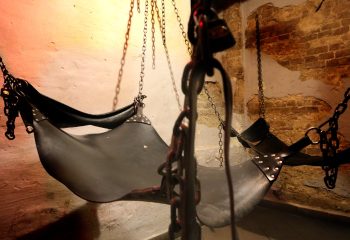 CoXx Men's Bar Budapest: Leather slings and chains hang in a dimly lit room. A gay bar with a kinky atmosphere for gay men travel.