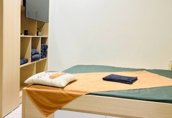 DaNi Spa Hanoi room. Massage bed with towels, pillow, and storage shelves. Gay travel advice for relaxation and wellness in Vietnam.