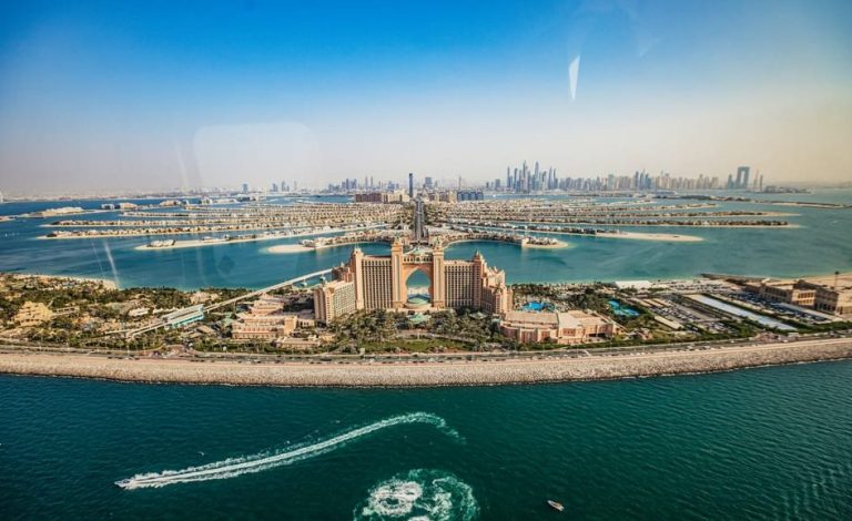 Dubai helicopter ride over The Palm, offering gay travel advice. Aerial view of Atlantis hotel, man-made islands, and city skyline.