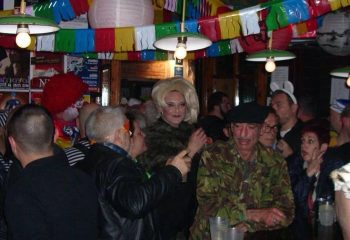 El Horno Gay Bar in Sitges: A lively scene inside, with people in costumes, colorful decorations, and a drag queen. Gay travel advice.