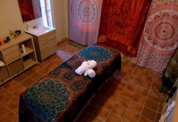 Maspalomas gay massage room in Gran Canaria. Massage table with towels, sink, cabinet, and mandalas on the wall. Gay travel advice.