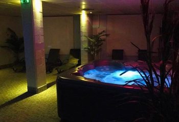 Flex Sauna: Indoor hot tub with blue water, lounge chairs, and plants. Relaxing spa day for gay men's travel.