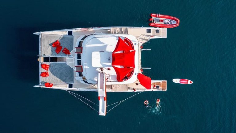Aerial view of a yacht in Pattaya, Thailand. Red accents, slide, & people swimming. Gay-friendly luxe day at sea for travel adventures.