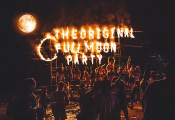 Koh Phangan Full Moon Party at Haad Rin. Crowd dancing under a Full Moon Party sign in flames. Gay dance beach bars visible.