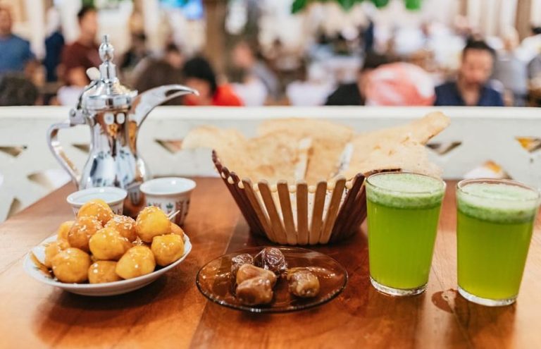 Dubai food adventure: Traditional Emirati treats. Dates, luqaimat, bread, juice, and coffee pot. Gay-friendly Dubai street food vibes.