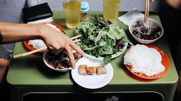 Hanoi street food tour: Bun cha meal with noodles, herbs, spring rolls, & dipping sauce. Gay-friendly bites in Vietnam's Train Street vibes.