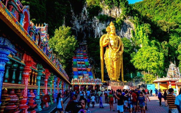 Gay-friendly Kuala Lumpur Batu Caves Cultural Temples Tour. Golden statue, colorful stairs, and temple at Batu Caves, Malaysia.