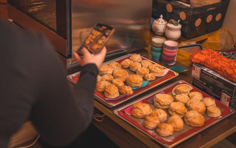 Gay-friendly London scone tea workshop: freshly baked scones on trays. Person taking a photo. Chic baking class in London, UK.