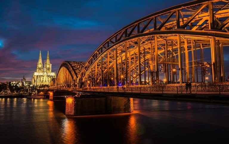 Cologne's Old Town highlights, a gay-friendly walking tour. The Hohenzollern Bridge and Cologne Cathedral at dusk. Travel advice for gay men.
