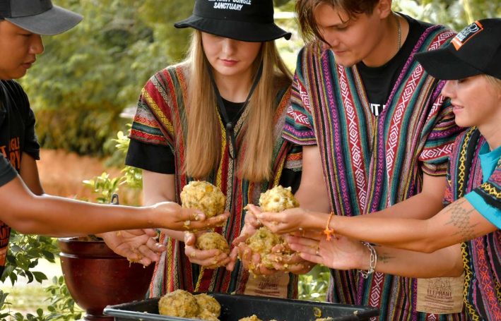 Gay travelers at Phuket Elephant Jungle Sanctuary experience. Volunteers prepare food for elephants during a Thai buffet. Ethical tourism.