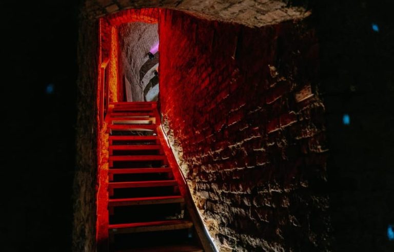Stairway to secrets: Guided tour of Vienna's underground. Red-lit stairs lead to a hidden passage, hinting at scandals and mysteries.