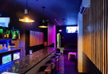 Interior of H2O Sauna, a gay sauna in Benidorm, Spain. Bar area with stools, drinks, and lounge seating. Nightlife scene.