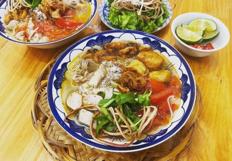 Hanoi Cooking Class dish. Vietnamese soup with tomatoes, fried tofu, herbs, and broth. Market Tour feast, LGTB friendly travel experience.