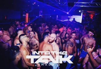 Into The Tank Madrid gay club: shirtless men dance under blue lights. Gay nightlife travel in Madrid, Spain.