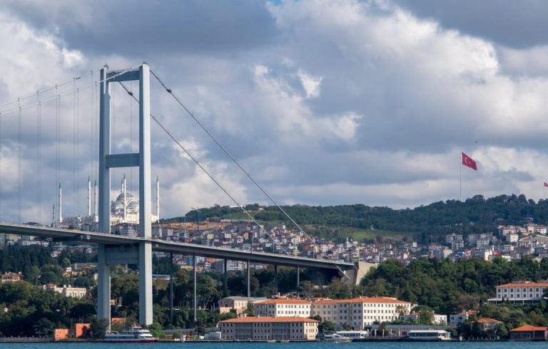 Istanbul sunset view with bridge, mosque, and Turkish flag. Chic scenic vibes for a gay yacht cruise, perfect for snacking and travel.