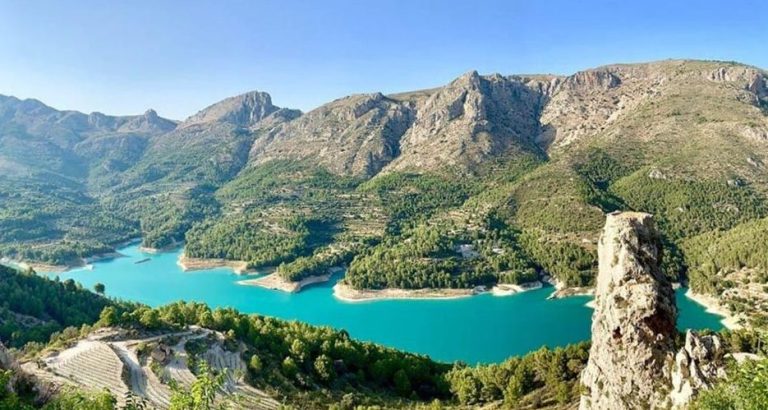 Guadalest Valley view, Costa Blanca. Turquoise lake surrounded by mountains and lush greenery. Perfect for gay travel adventure.
