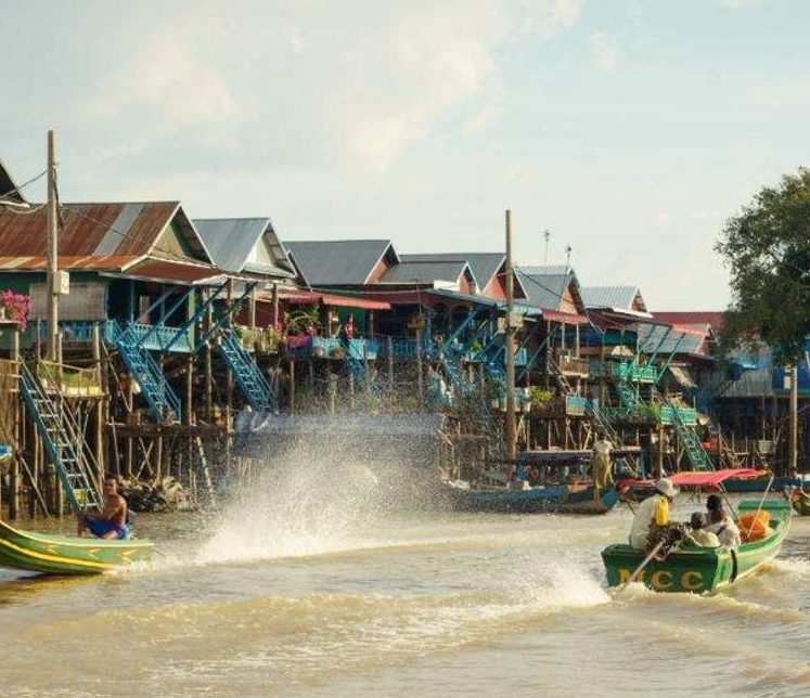 Kampong Phluk floating village, Tonle Sap. Boat adventure in Siem Reap, Cambodia. Gay travel to Southeast Asia. Houses on stilts, water view.